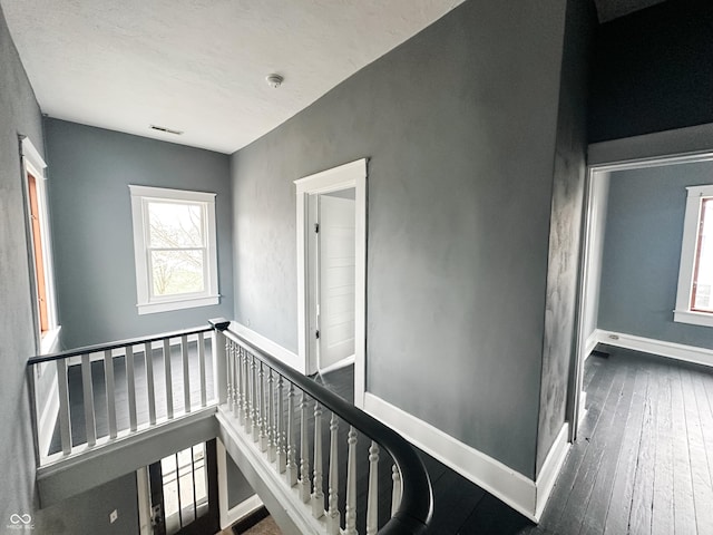stairs featuring baseboards, hardwood / wood-style flooring, and visible vents