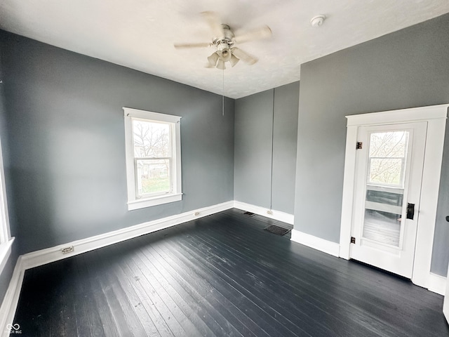 unfurnished room with a ceiling fan, dark wood finished floors, and plenty of natural light