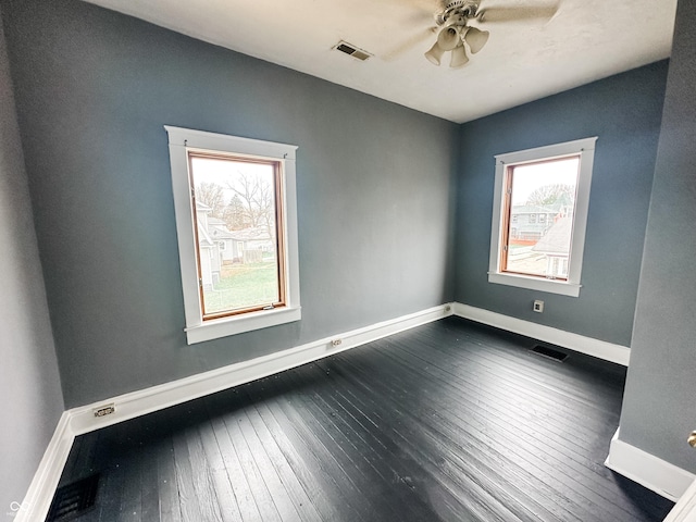 unfurnished room with visible vents, dark wood-style flooring, ceiling fan, and baseboards