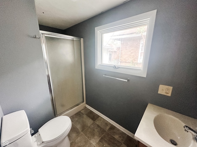 full bathroom featuring baseboards, a sink, a stall shower, and toilet