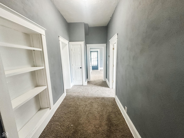 hallway featuring baseboards and carpet flooring