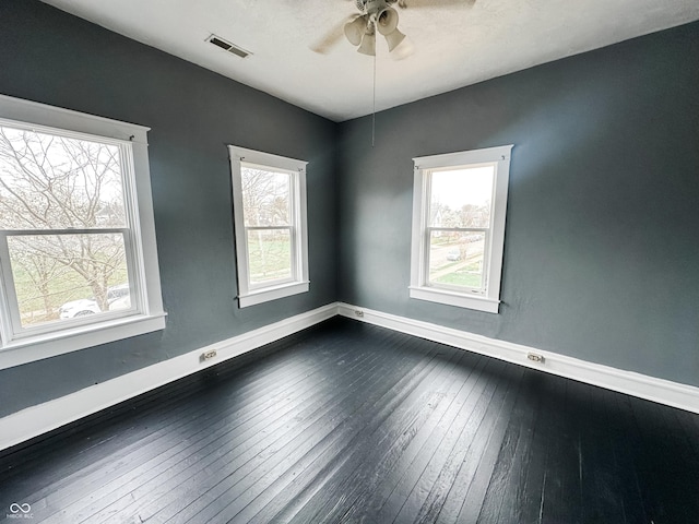 unfurnished room with ceiling fan, visible vents, a healthy amount of sunlight, and dark wood-type flooring