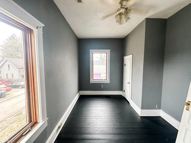unfurnished room with baseboards, dark wood-style flooring, and ceiling fan