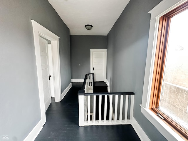 hallway with baseboards, wood finished floors, and a healthy amount of sunlight
