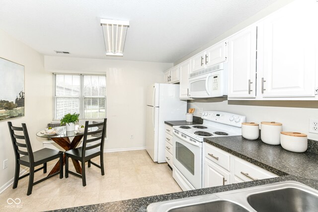 kitchen featuring visible vents, white appliances, dark countertops, white cabinetry, and a sink