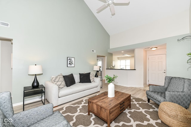 living room with high vaulted ceiling, a ceiling fan, wood finished floors, baseboards, and visible vents