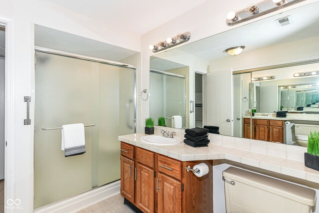 full bathroom featuring a stall shower, visible vents, toilet, and vanity