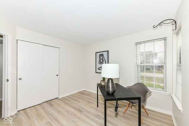 office featuring baseboards, light wood finished floors, and a textured ceiling