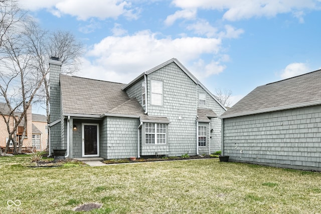 back of house with a lawn, a chimney, and a shingled roof