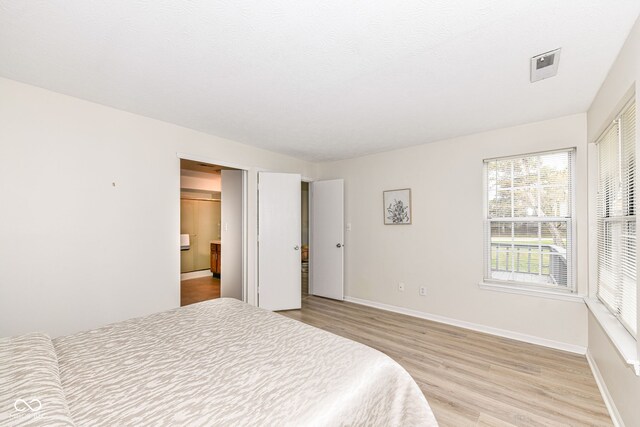 bedroom featuring light wood finished floors and baseboards