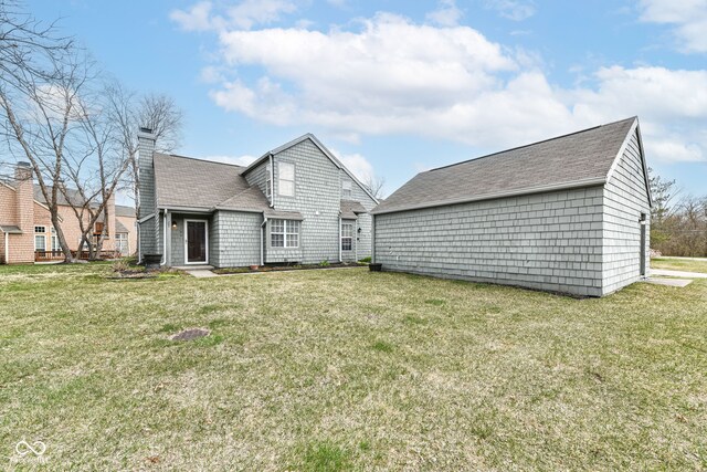 rear view of property featuring a lawn and a chimney