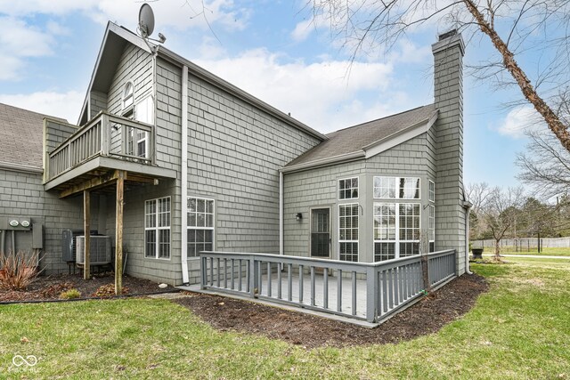 rear view of house featuring a balcony, a chimney, central AC, and a yard