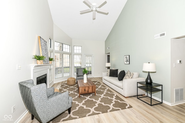living area with a ceiling fan, wood finished floors, a fireplace, and visible vents