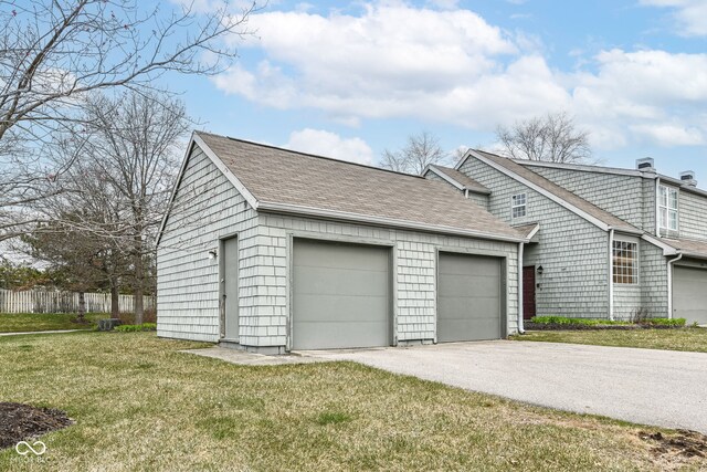 view of side of home featuring roof with shingles, fence, an attached garage, driveway, and a yard