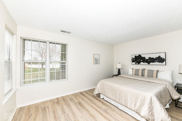 bedroom featuring baseboards, light wood-style floors, and visible vents
