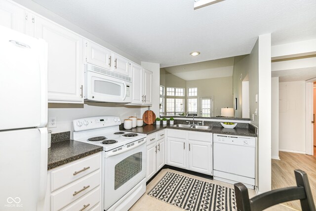 kitchen with white cabinets, a sink, light wood finished floors, and white appliances