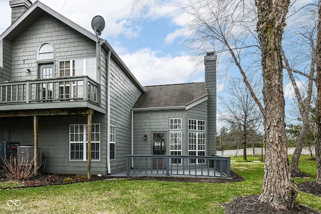 rear view of property with a lawn, a chimney, and a deck