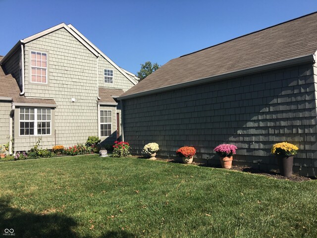 exterior space with a shingled roof and a yard