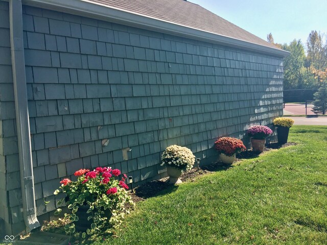 view of home's exterior with a yard, fence, and roof with shingles