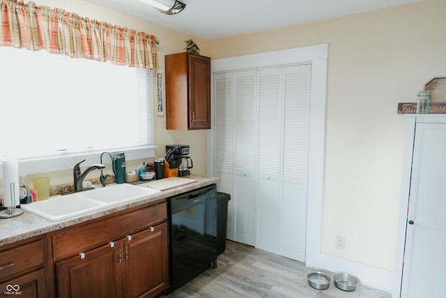 kitchen with light countertops, light wood-style flooring, a sink, black dishwasher, and brown cabinetry