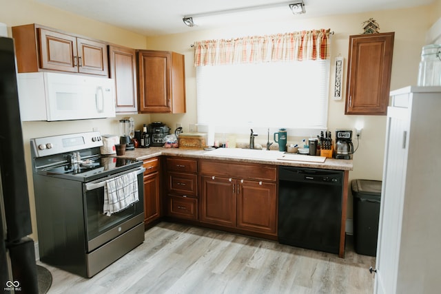 kitchen featuring light countertops, a sink, light wood-style flooring, black appliances, and brown cabinetry