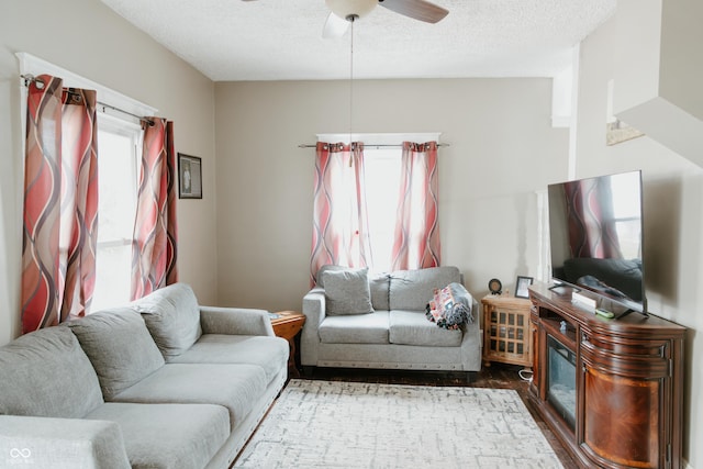 living area with wood finished floors, ceiling fan, and a textured ceiling