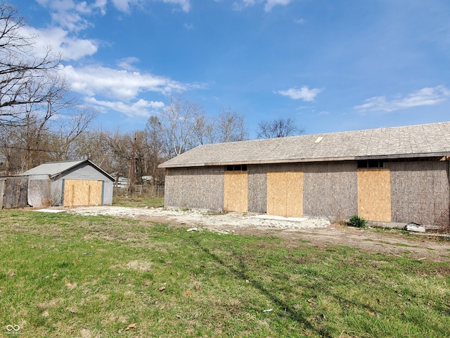 view of side of property with a lawn and an outbuilding
