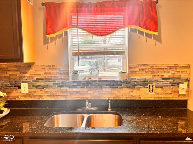 kitchen featuring dark stone counters, a sink, and tasteful backsplash