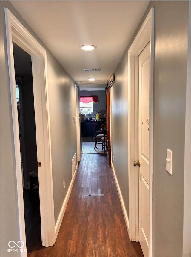 hall with dark wood-style flooring, baseboards, and visible vents