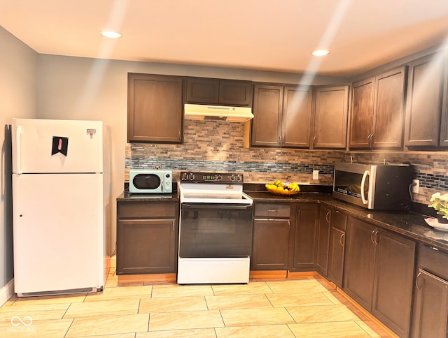 kitchen featuring under cabinet range hood, dark stone countertops, white appliances, decorative backsplash, and recessed lighting