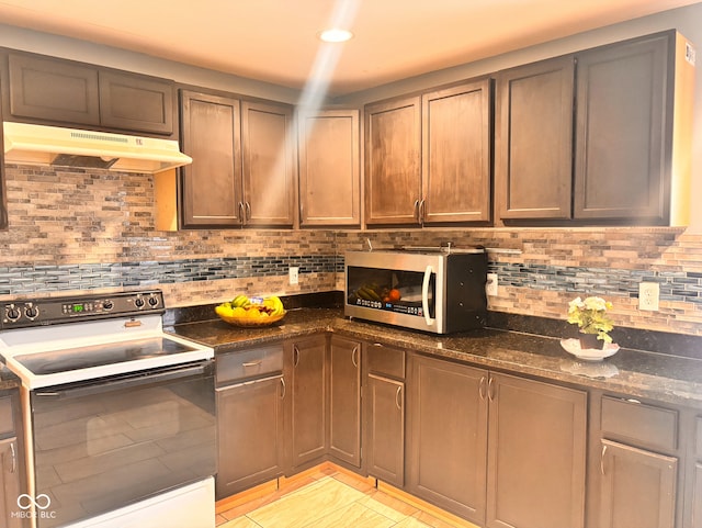 kitchen featuring backsplash, white range with electric stovetop, under cabinet range hood, stainless steel microwave, and dark stone counters