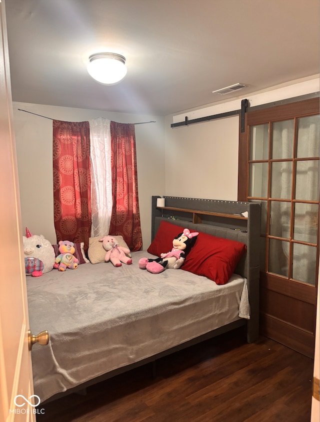 bedroom with visible vents, a barn door, and wood finished floors