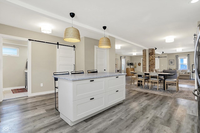 934 E Minnesota St, Indianapolis, IN 46203 - kitchen with white cabinetry, a barn door, light stone countertops, open floor plan, and light wood-type flooring