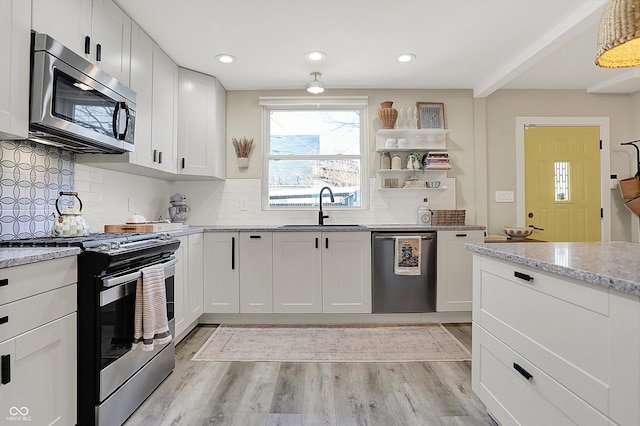 934 E Minnesota St, Indianapolis, IN 46203 - kitchen with decorative backsplash, light wood finished floors, stainless steel appliances, white cabinetry, and a sink