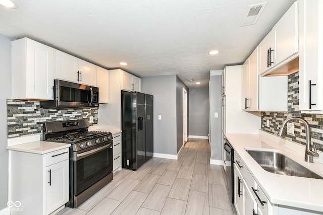 kitchen featuring a sink, appliances with stainless steel finishes, visible vents, light countertops, and baseboards