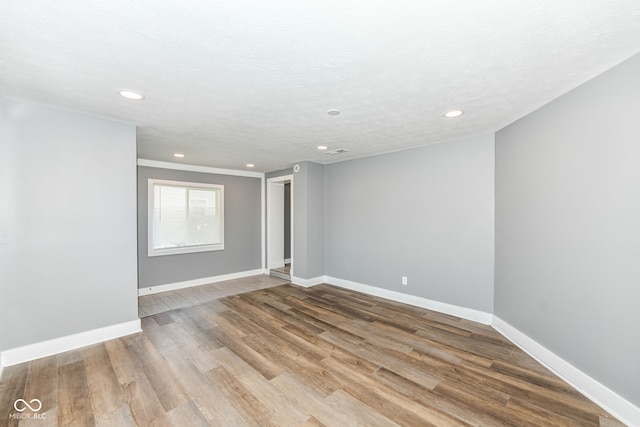 empty room featuring wood finished floors, recessed lighting, and baseboards