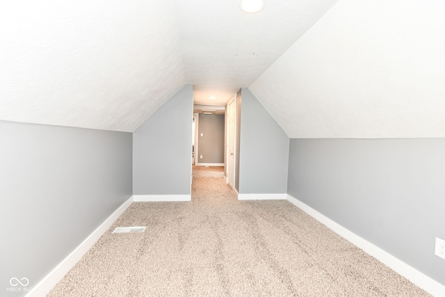 bonus room featuring lofted ceiling, visible vents, baseboards, and carpet floors