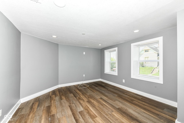 spare room featuring dark wood-style floors, recessed lighting, a textured ceiling, and baseboards