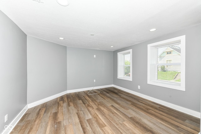 empty room featuring recessed lighting, wood finished floors, and baseboards