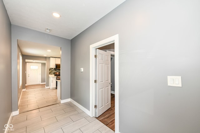 corridor featuring wood tiled floor, recessed lighting, visible vents, and baseboards