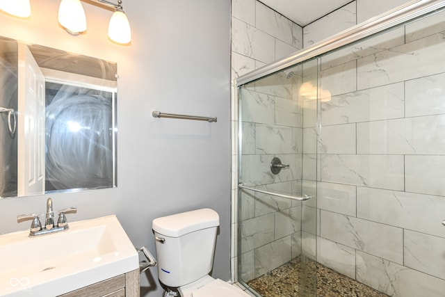 bathroom featuring toilet, a shower stall, and vanity