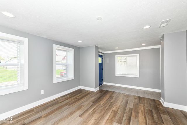 unfurnished room featuring baseboards, recessed lighting, wood finished floors, and a healthy amount of sunlight