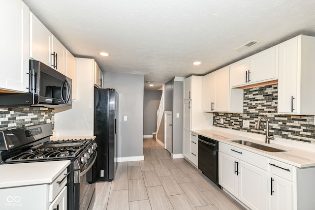 kitchen with a sink, visible vents, light countertops, baseboards, and black appliances