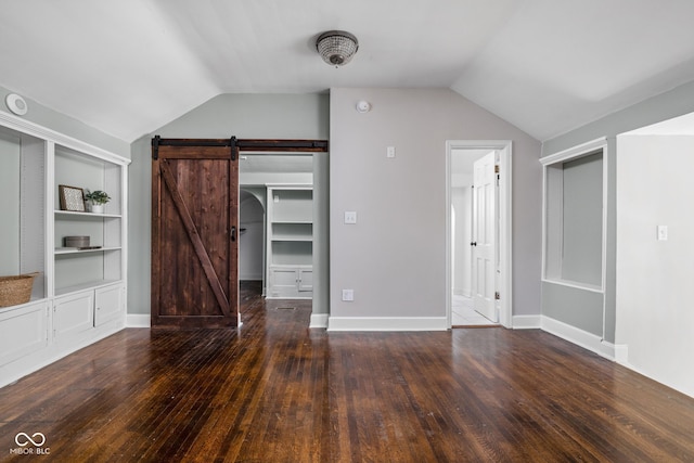 3447 Washington Blvd, Indianapolis, IN 46205 - unfurnished living room with a barn door, lofted ceiling, hardwood / wood-style flooring, and built in shelves