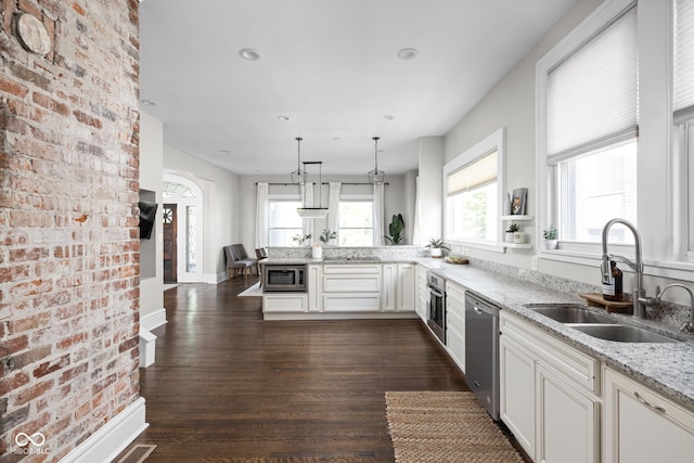 3447 Washington Blvd, Indianapolis, IN 46205 - kitchen featuring a sink, stainless steel appliances, a peninsula, light stone counters, and dark wood-type flooring
