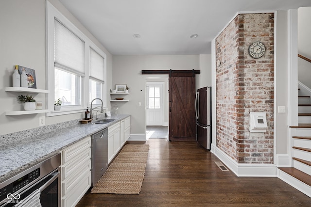3447 Washington Blvd, Indianapolis, IN 46205 - kitchen featuring open shelves, appliances with stainless steel finishes, a sink, light stone countertops, and a barn door