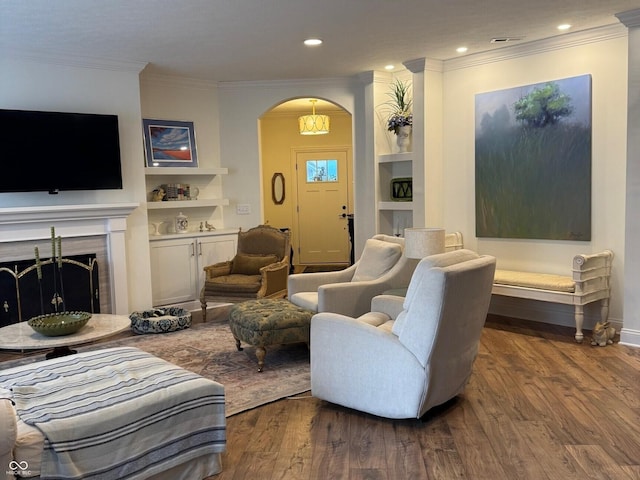 2460 Collins Dr, Westfield, IN 46074 - living area featuring wood finished floors, arched walkways, built in features, ornamental molding, and a fireplace with raised hearth