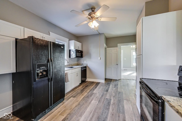 kitchen with white cabinets, black appliances, light wood-style flooring, and ceiling fan