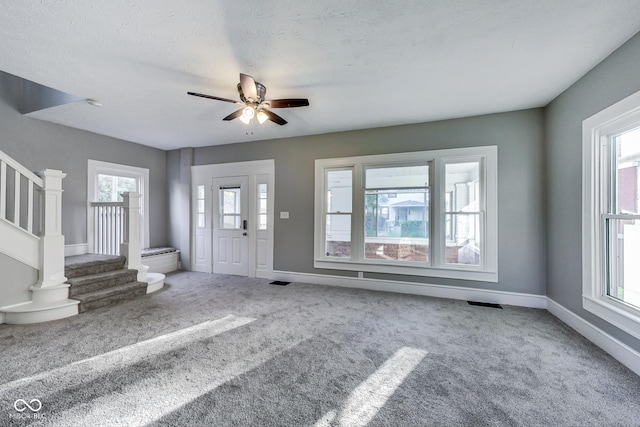 entrance foyer with stairs, carpet flooring, and plenty of natural light