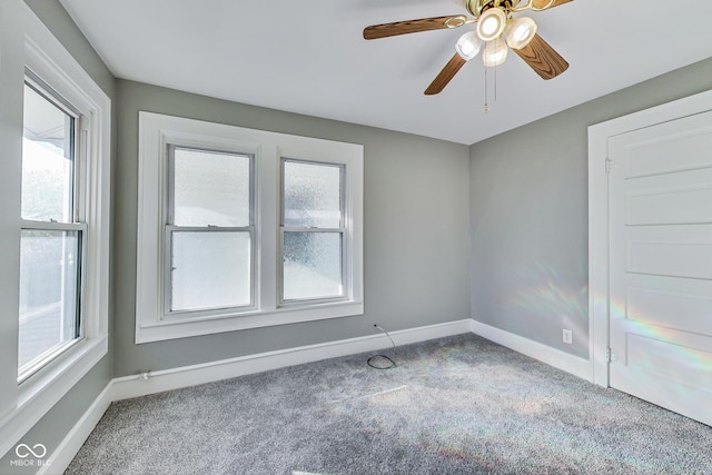 carpeted empty room with baseboards and a ceiling fan